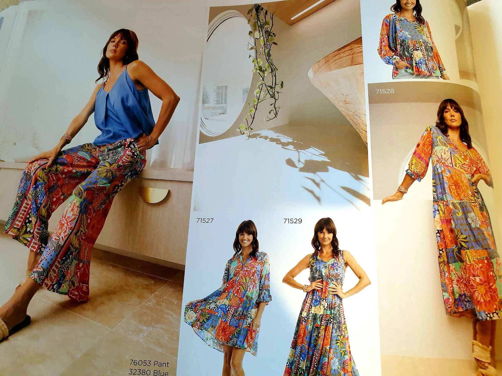 Woman in blue top and patterned pants sits; other women in colorful dresses pose.