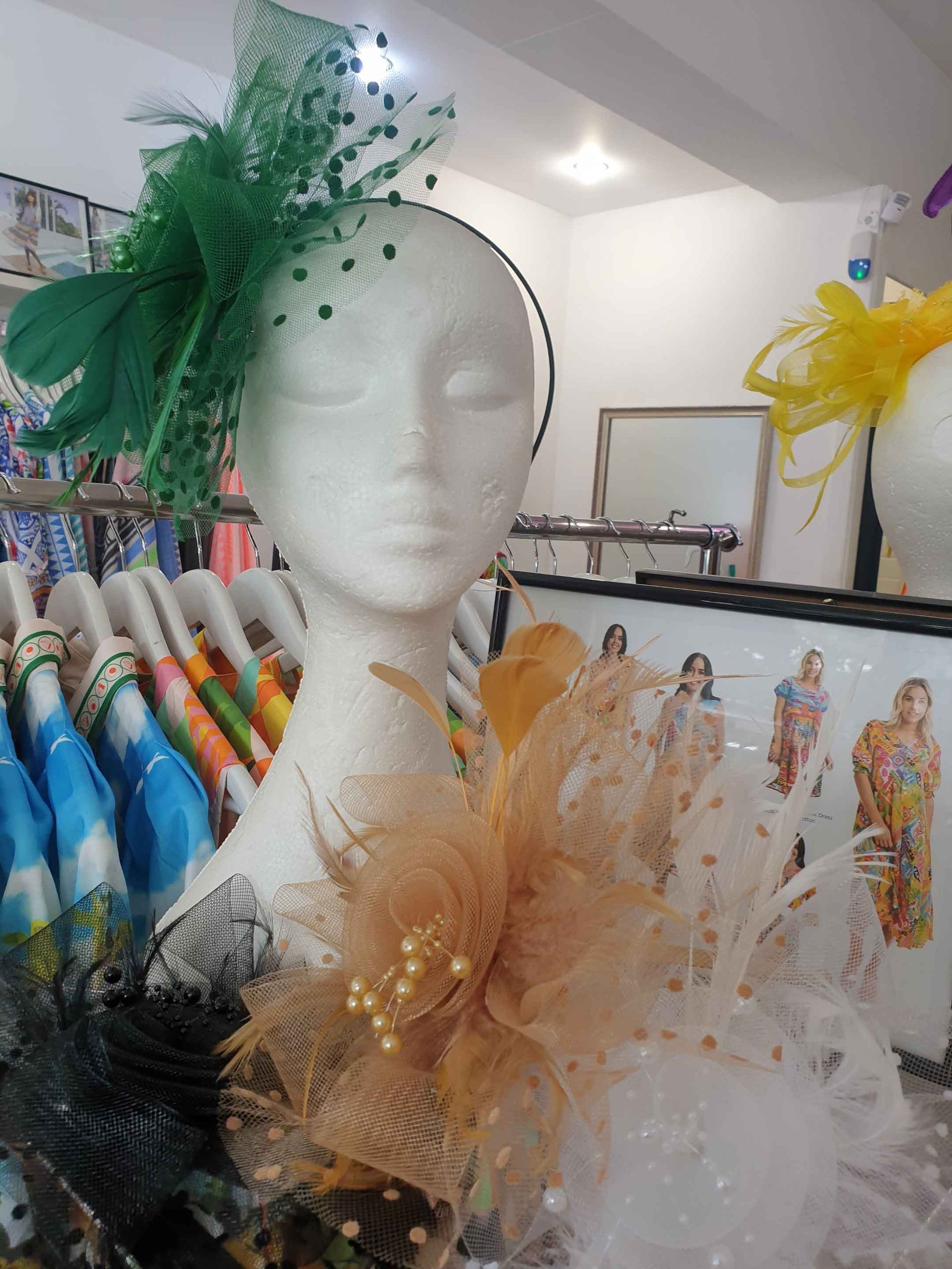 Mannequin head wearing green and gold headwear, in a shop.