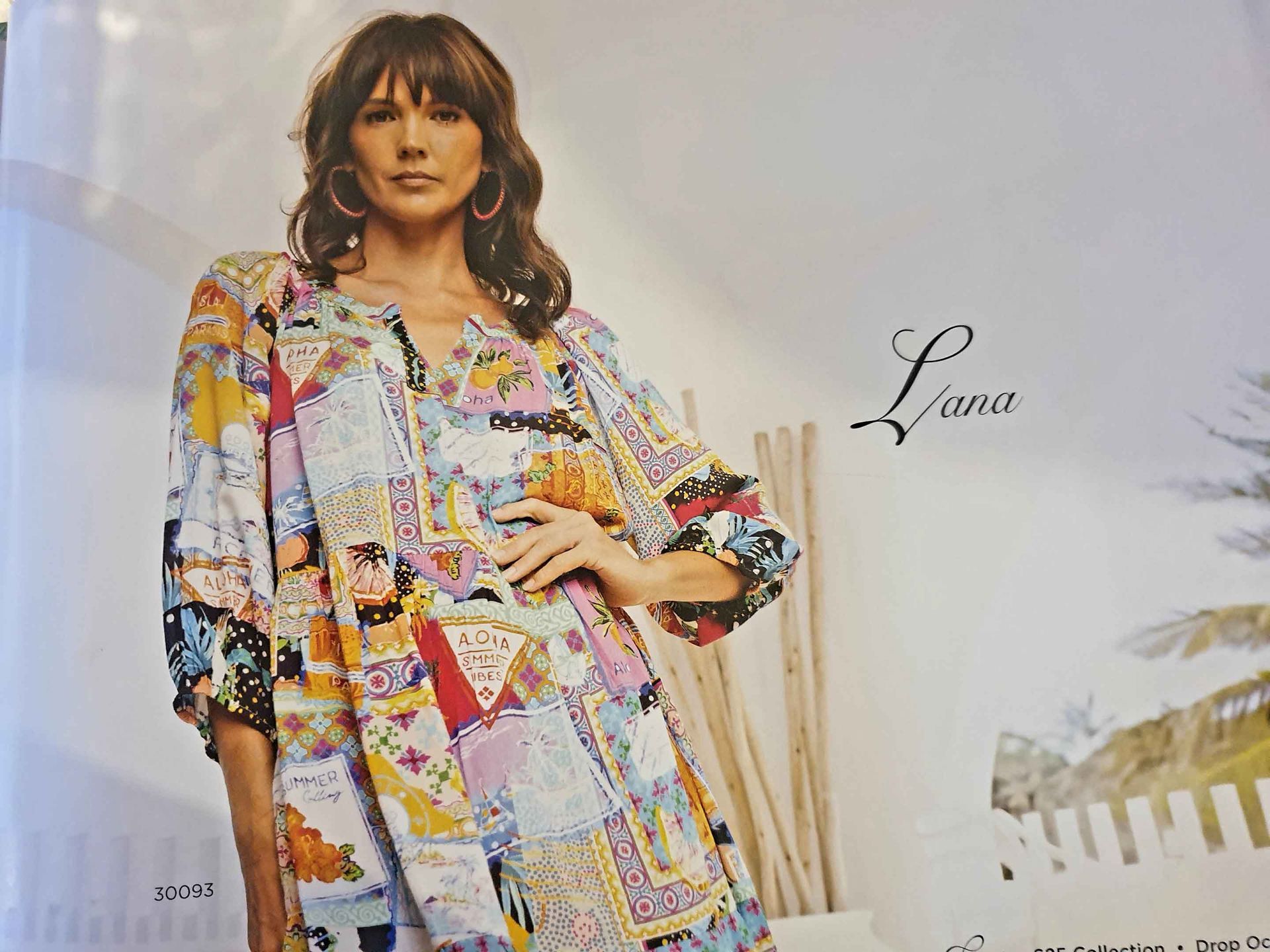 Woman in colorful patchwork dress posing outside, hand on hip.