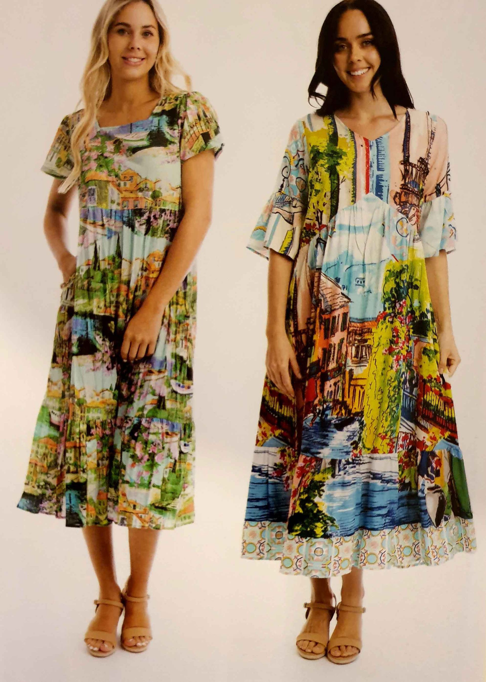 Two women wearing colorful landscape-print midi dresses; one with short sleeves, the other with flared sleeves; both smiling.