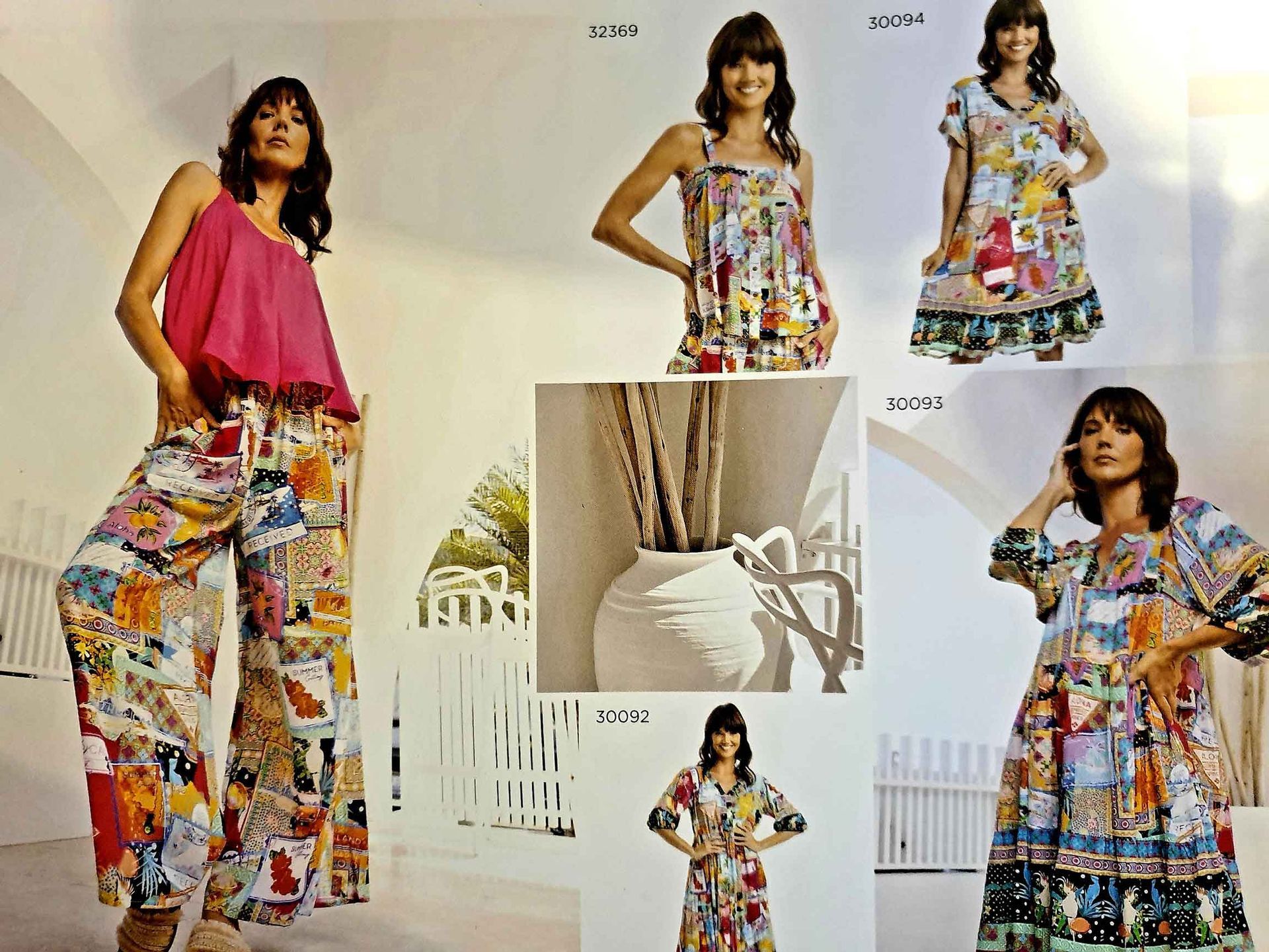 Woman modeling colorful patchwork clothing in a bright setting.