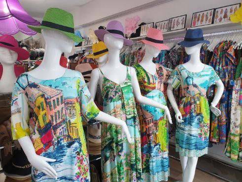 Mannequins wearing colorful dresses and hats in a clothing store.