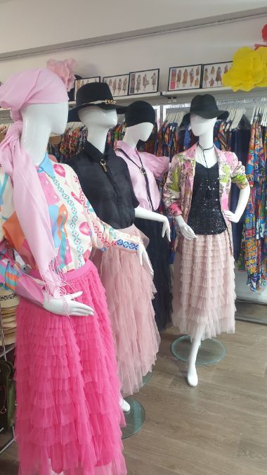 Four mannequins wearing colorful outfits inside a clothing store.