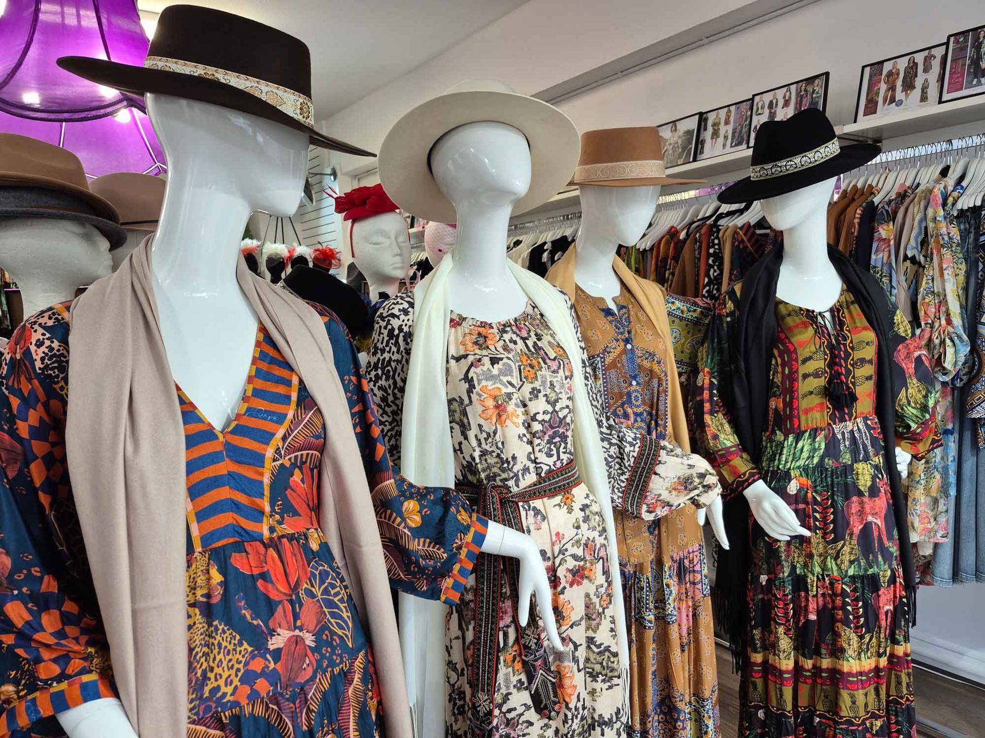 Mannequins in a clothing store wearing floral dresses and hats.