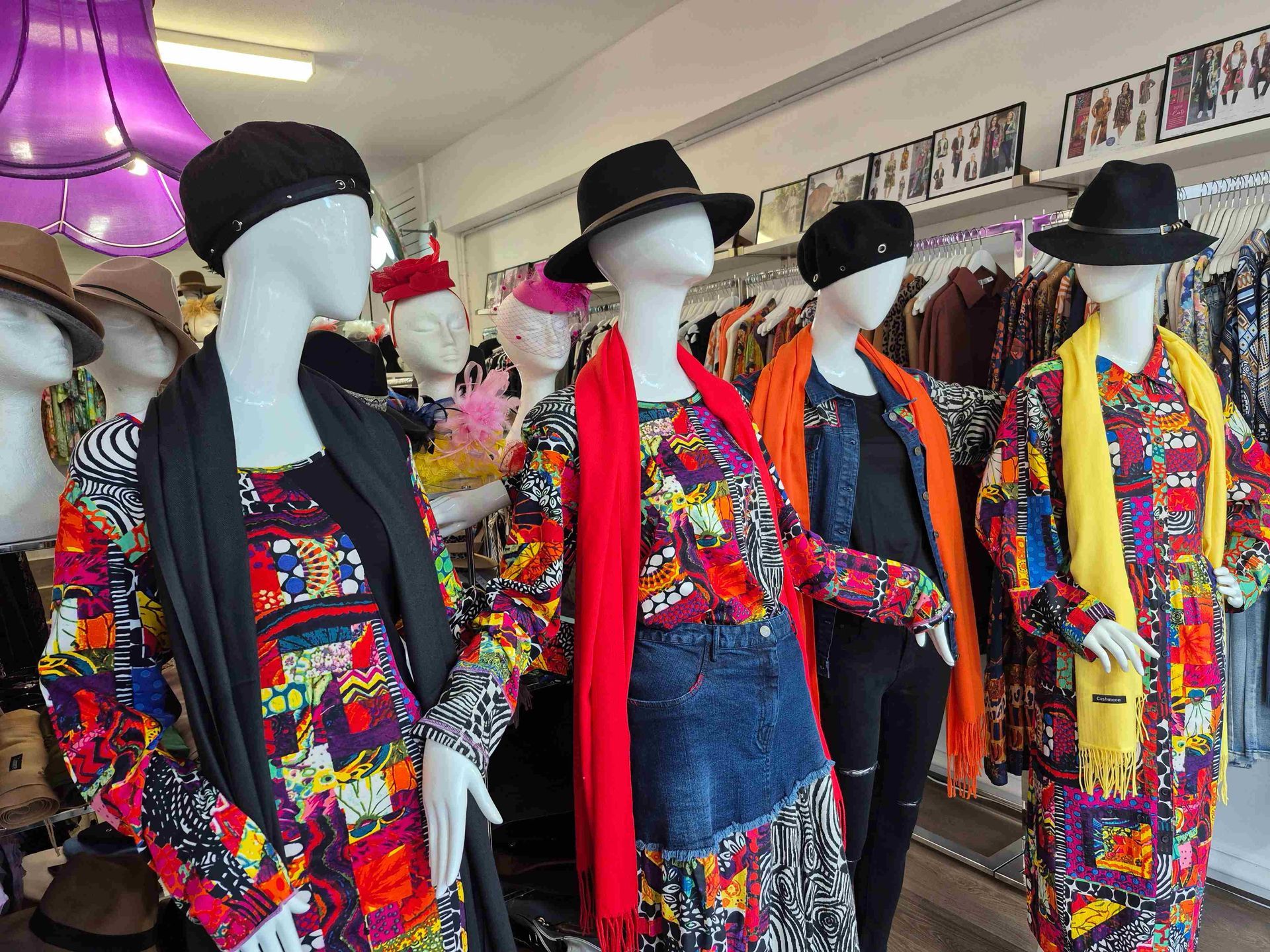 Mannequins in a clothing store wearing colorful patterned outfits, hats, and scarves.