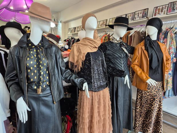 Mannequins in vintage clothing, including leather jackets, skirts, and hats. Various colors, inside a boutique.