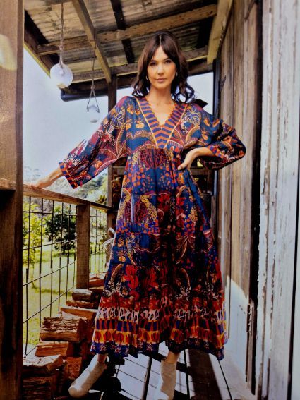 Woman in patterned blue dress on wooden deck.