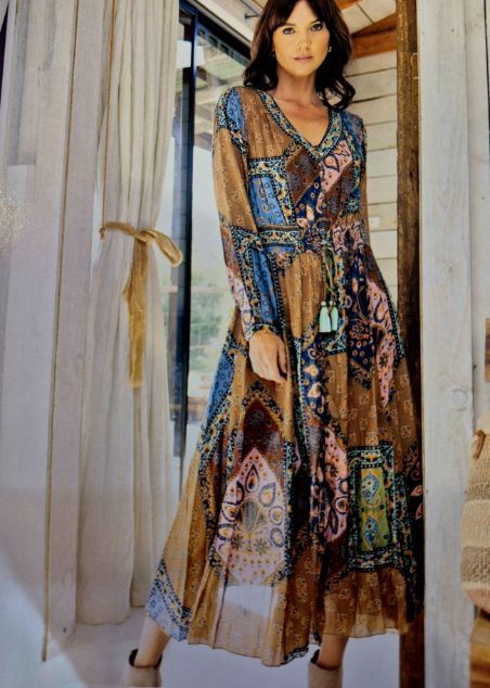 Woman in long, patterned dress, standing in doorway. Dress has blue, tan, and pink accents.