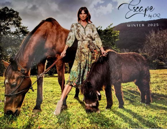 Woman in patterned dress with two horses in a field, 