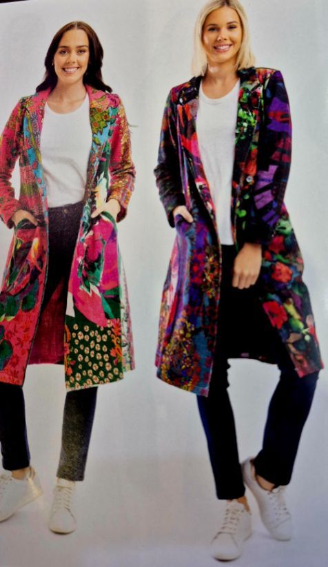 Two women wearing colorful patterned long coats, white shirts, dark pants, and sneakers.
