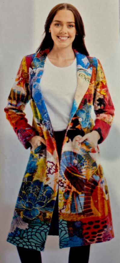 Woman wearing a long, colorful coat with abstract artwork, smiling at the camera.