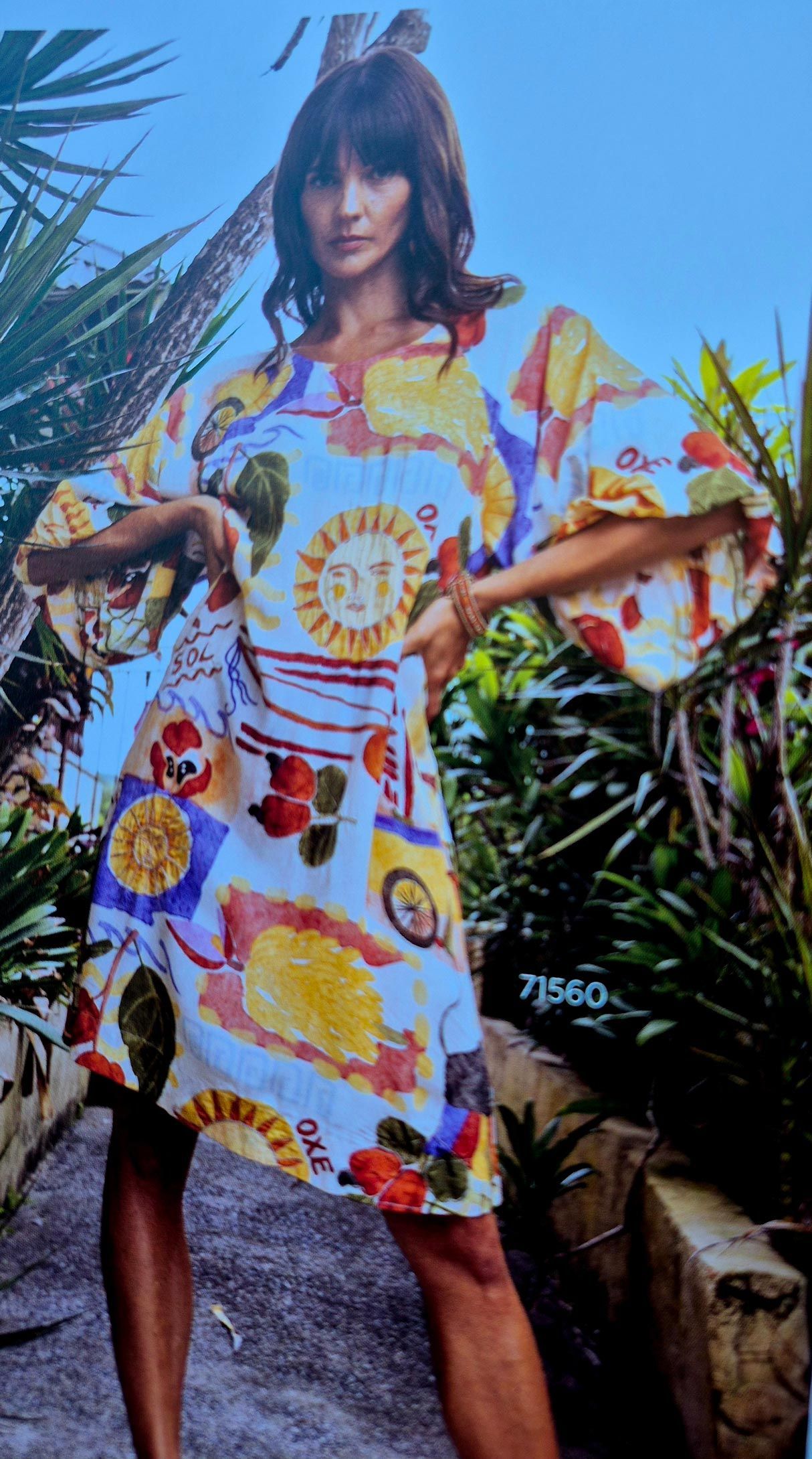 Woman in colorful printed dress poses outdoors.