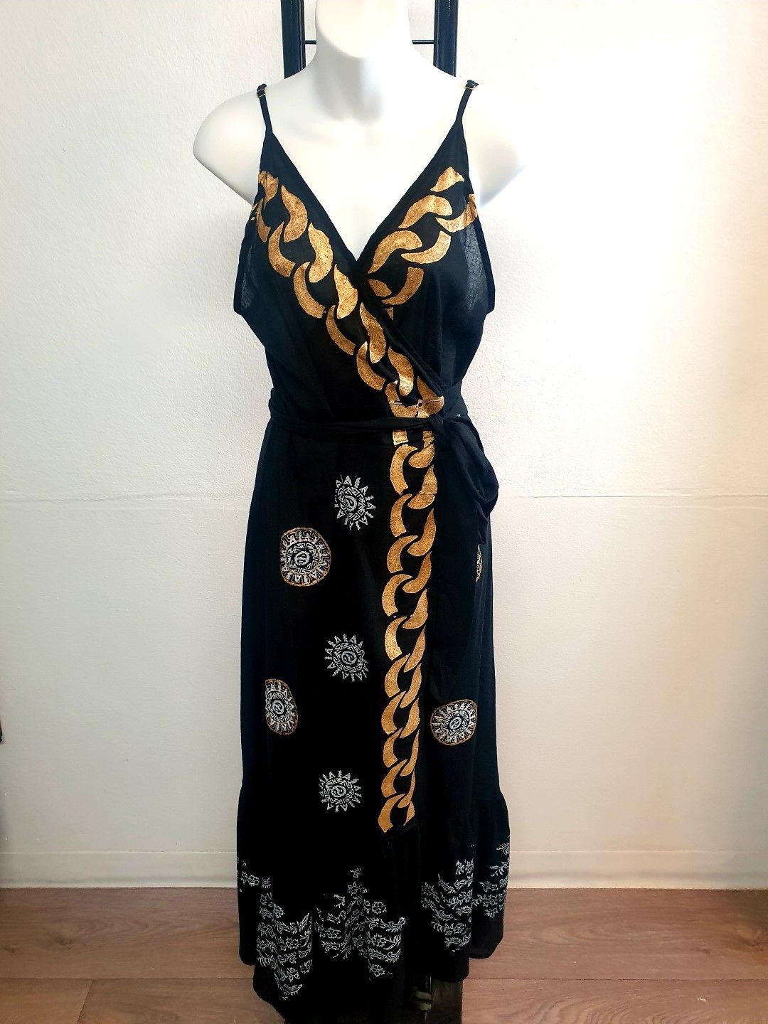 Black wrap dress with gold chain-like embellishments on a mannequin.