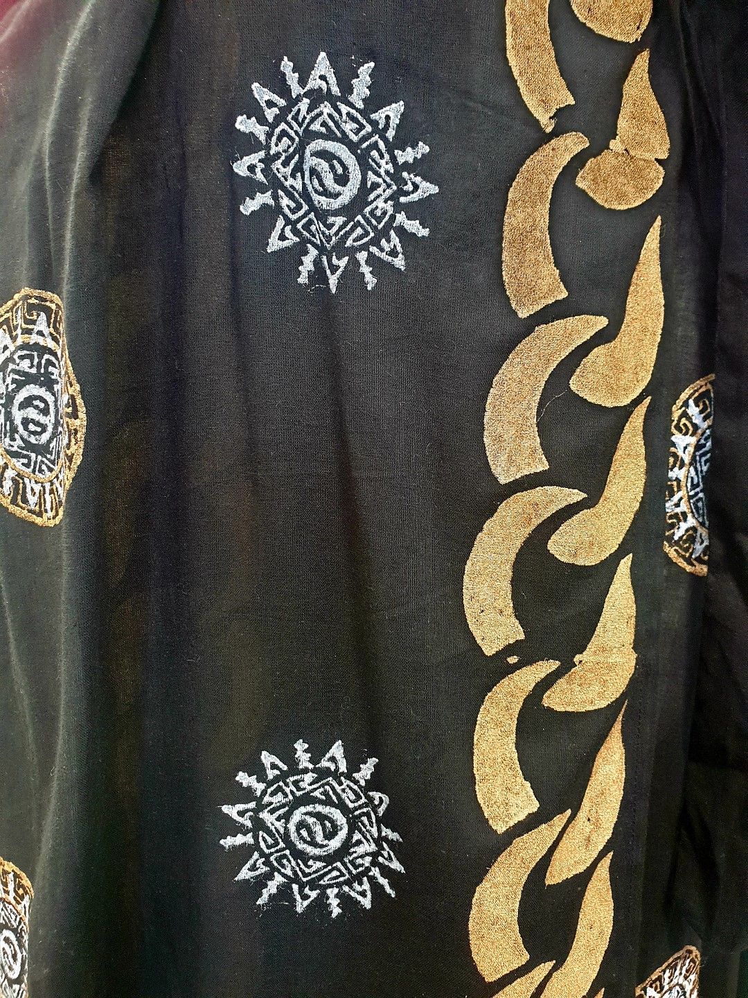 Black fabric with gold chain and sunburst patterns.