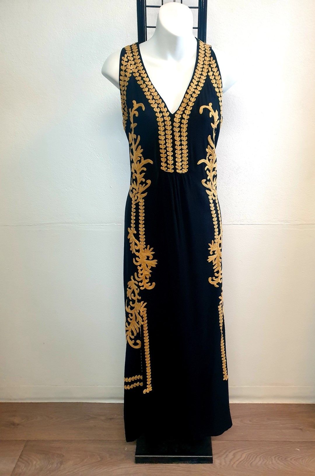 Black sleeveless maxi dress on a mannequin, with gold embroidery down the front and sides.