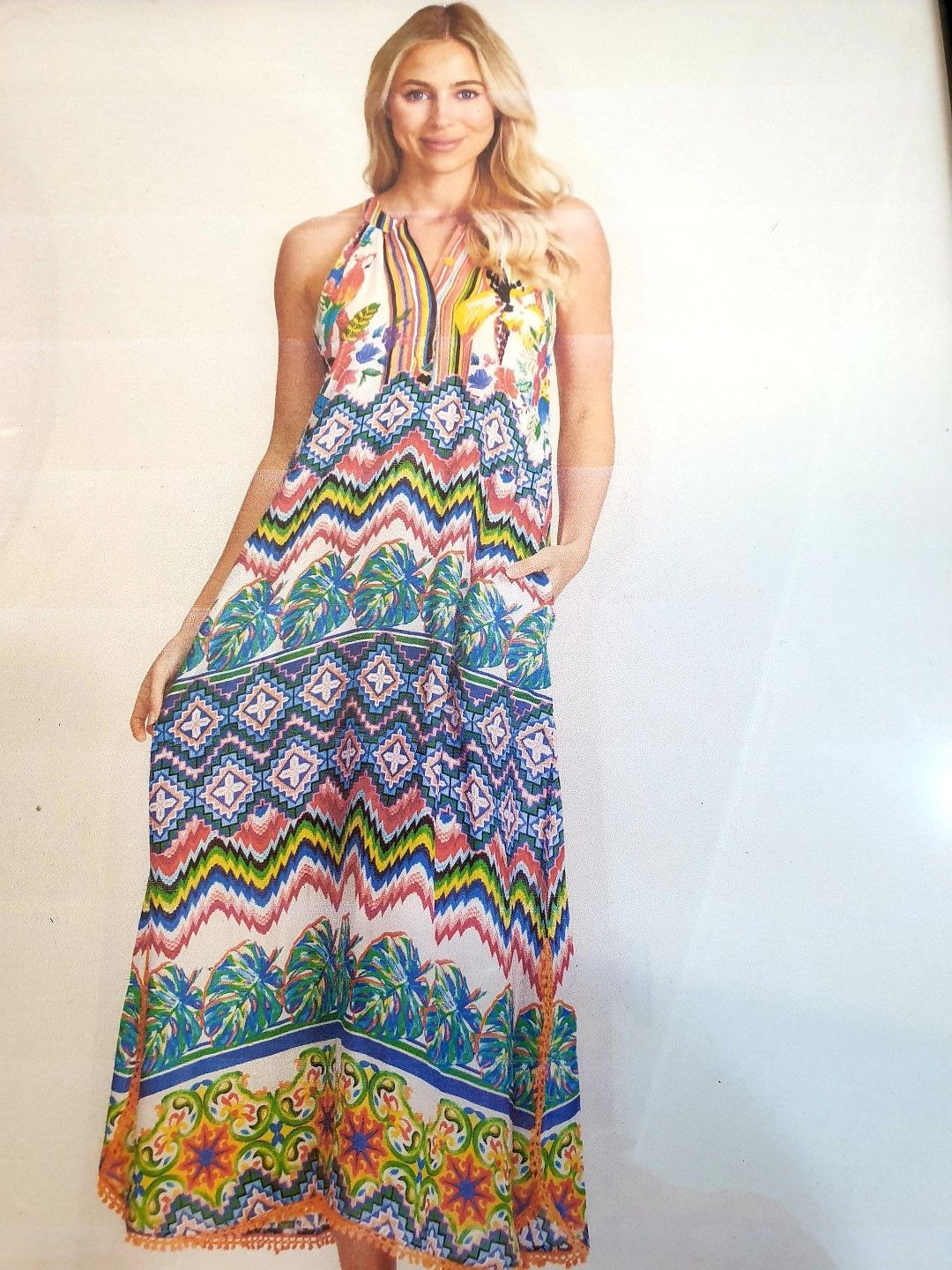 Woman wearing a colorful patterned halter maxi dress, standing.