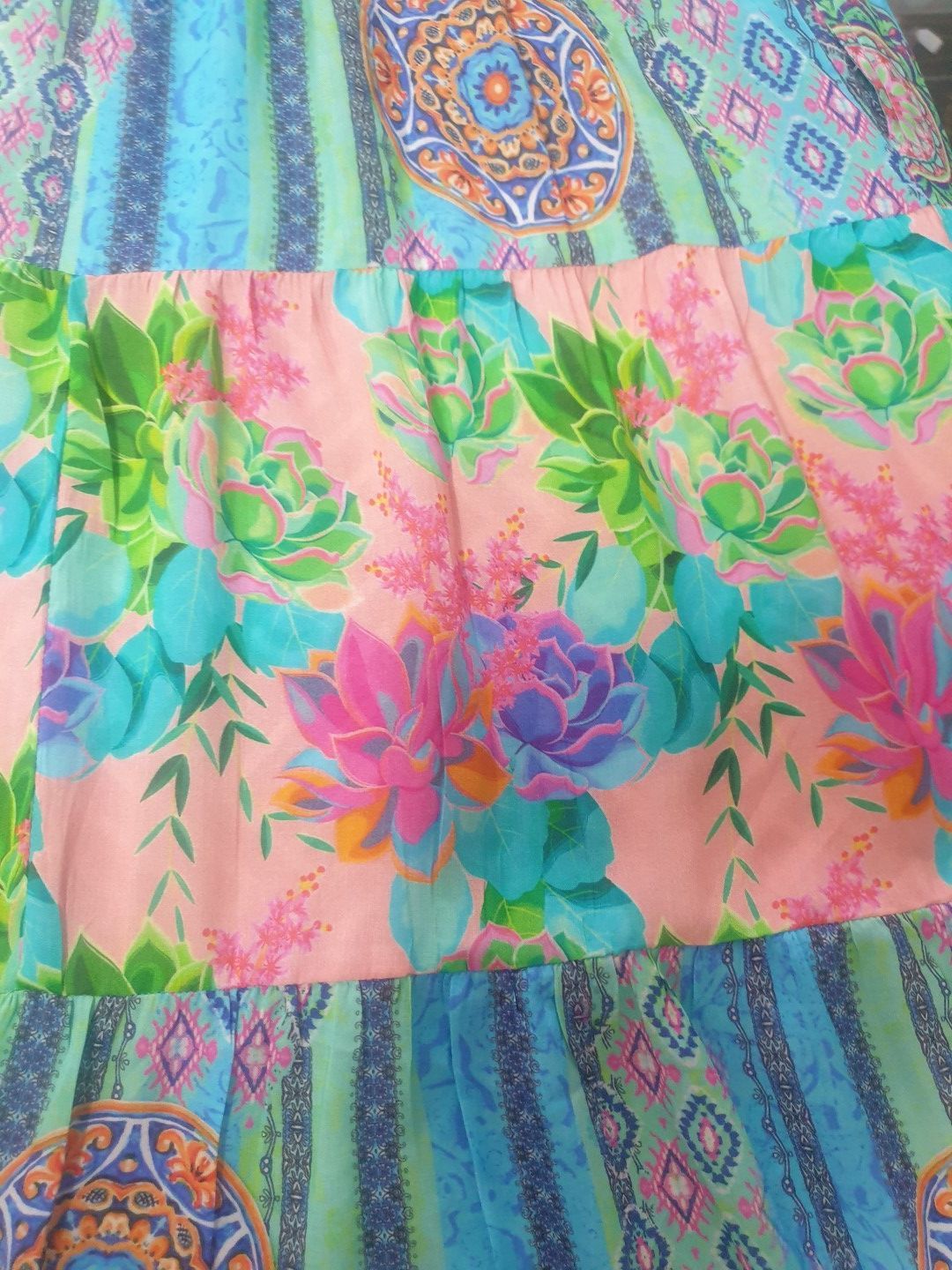 Tiered skirt with colorful floral, geometric, and stripe patterns in shades of blue, green, and pink.