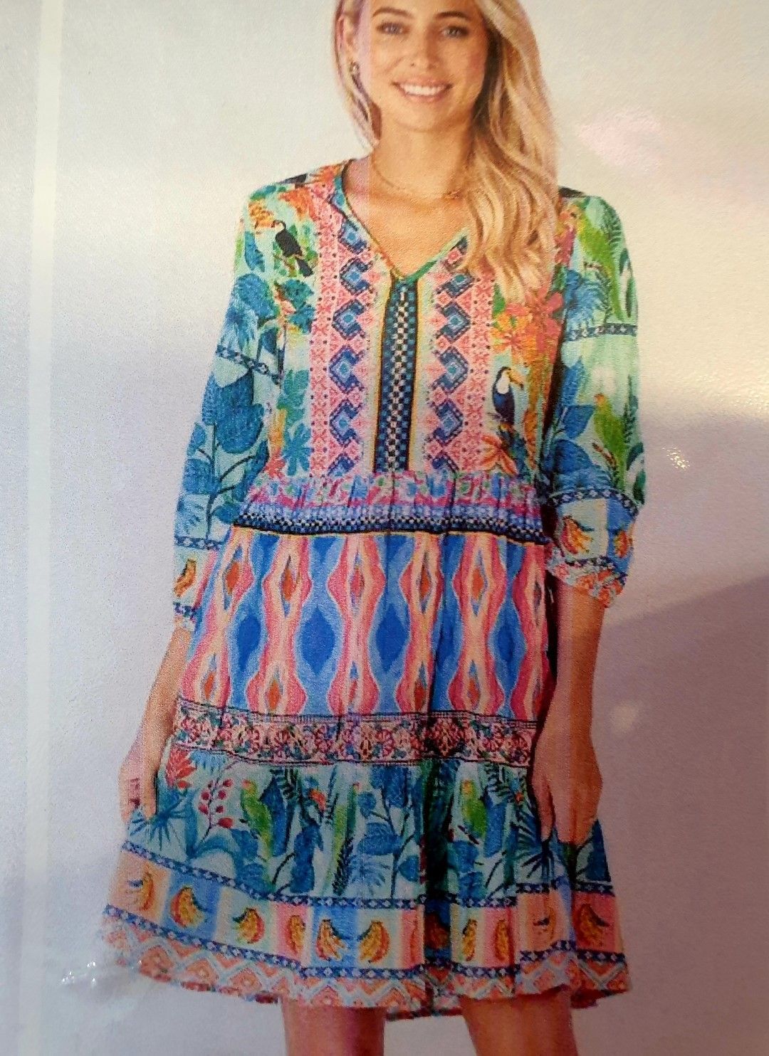 Woman wearing a colorful floral-print dress with a V-neck, smiles.