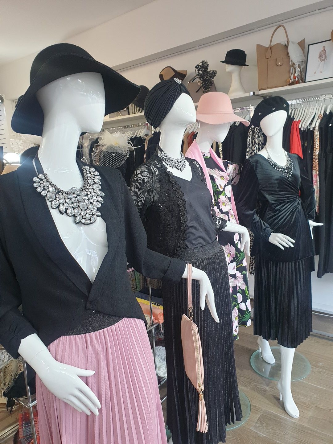 Mannequins wearing vintage-style clothing, including hats, necklaces, and skirts, in a clothing store.
