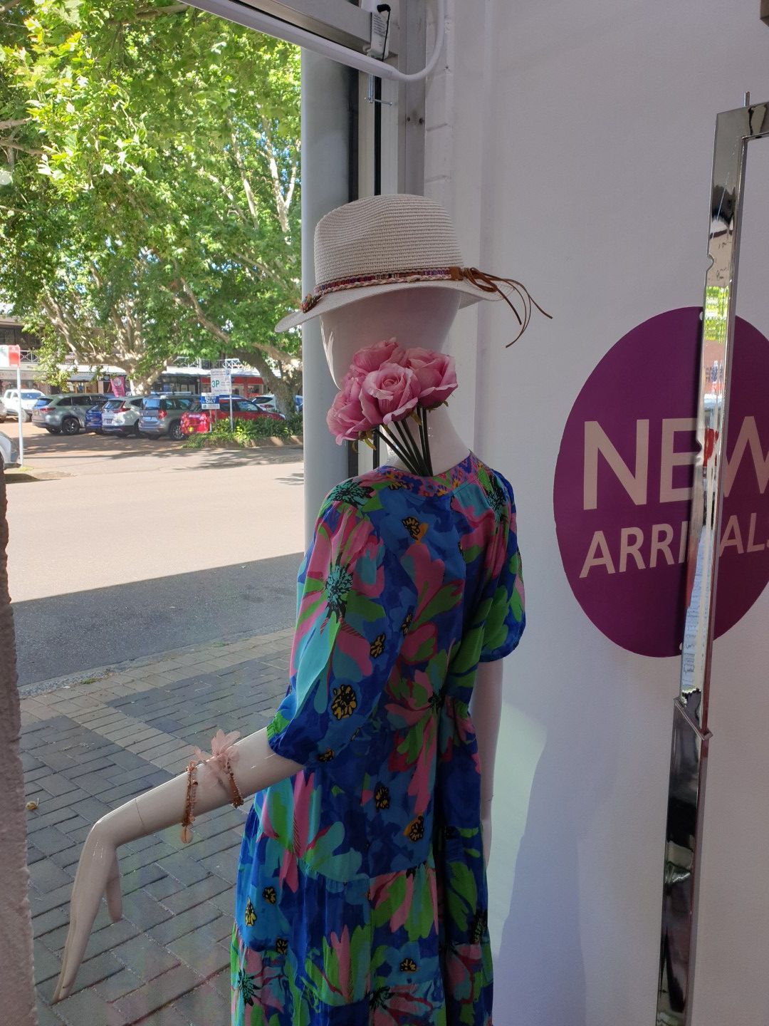 Mannequin in floral dress and hat, by a window. 
