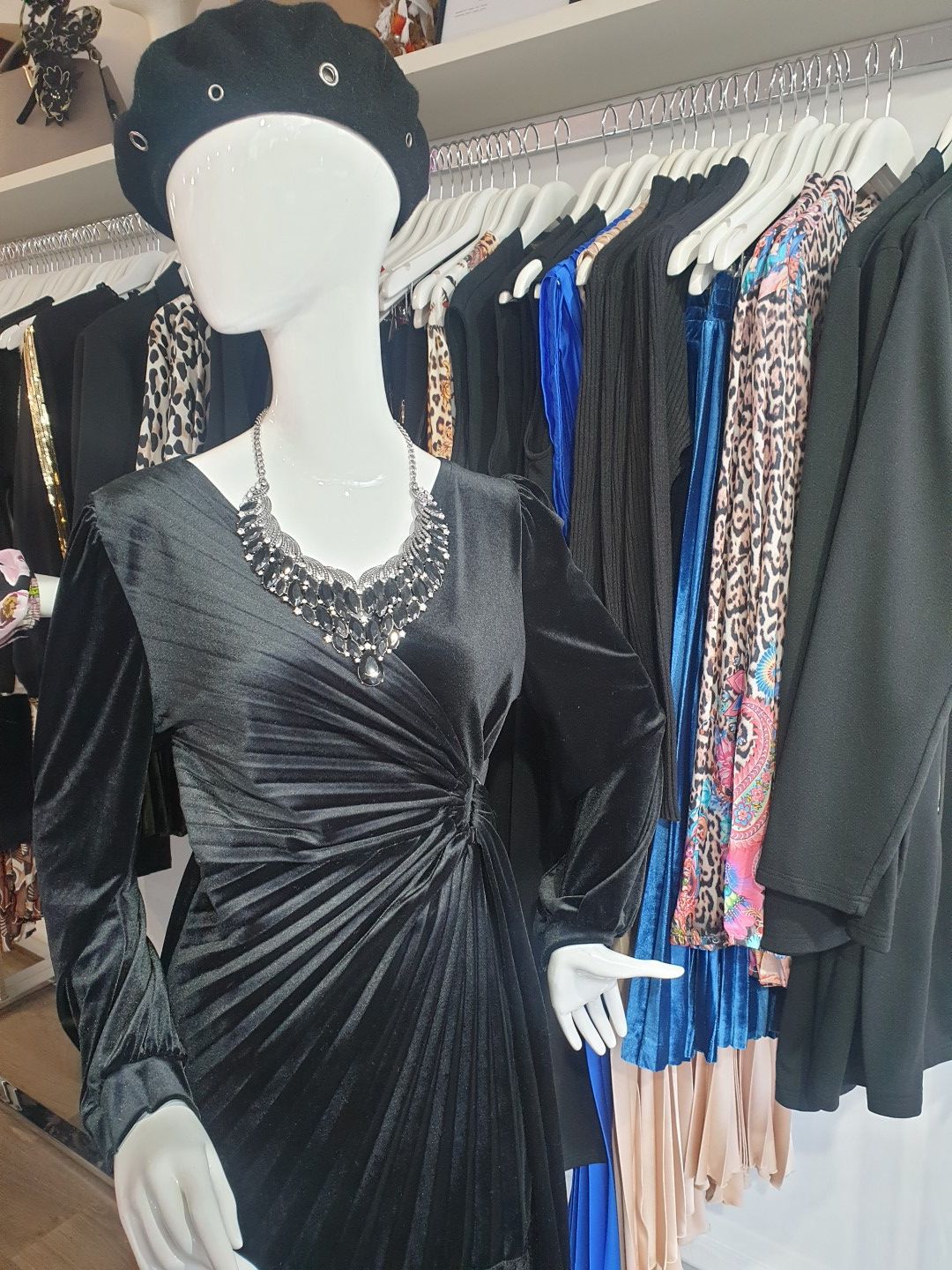Mannequin in black velvet dress, beret, and necklace, displayed in a clothing store.