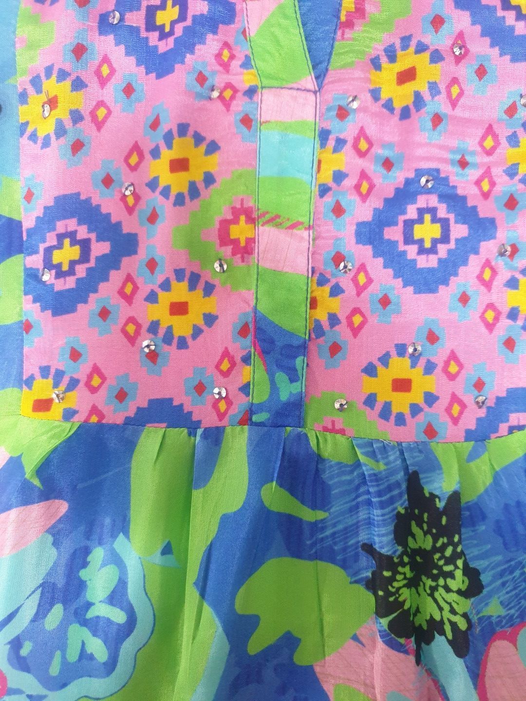 Pink patterned shirt with blue, green, and yellow details; a V-neck and pleats.