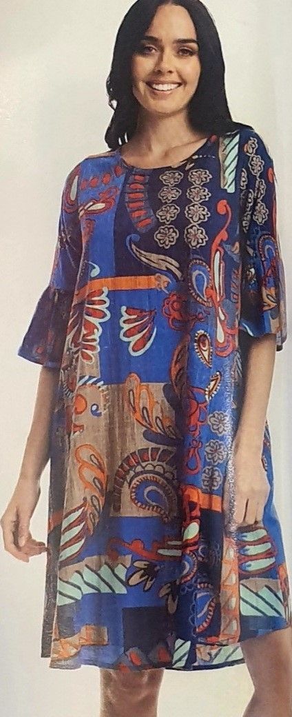 Woman wearing a patterned blue dress, smiling, with dark hair.