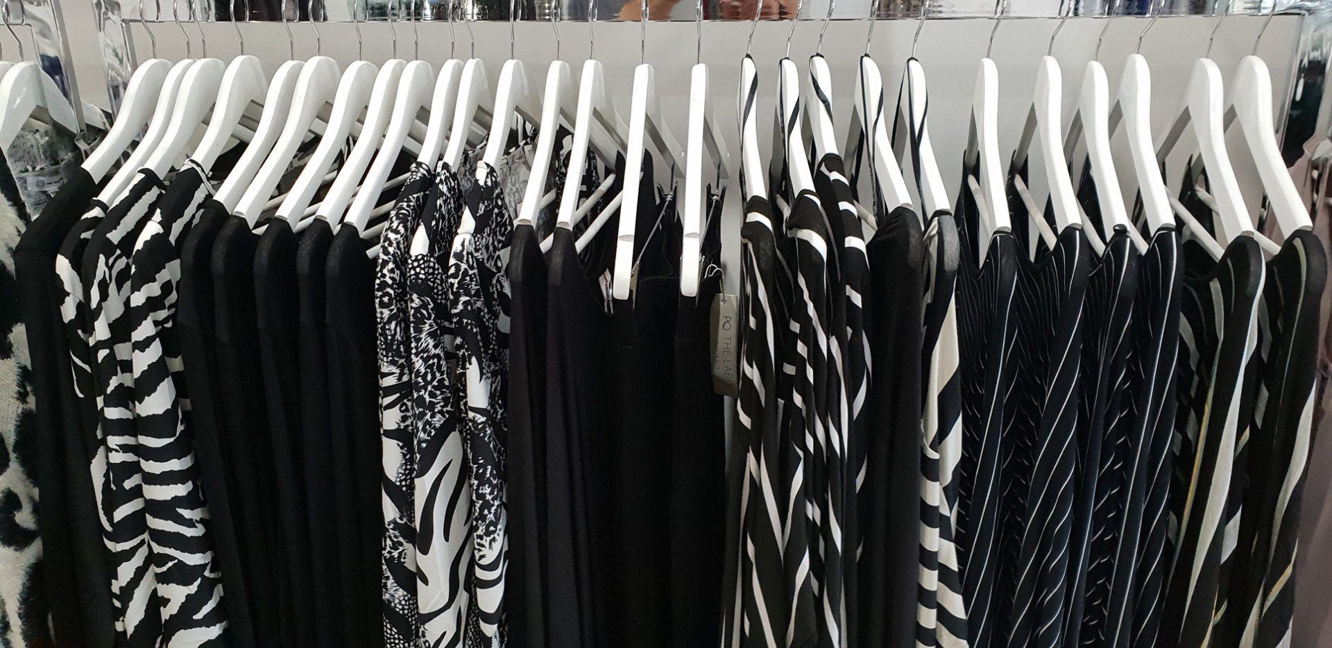 Clothes hanging on white hangers, mostly black and white patterns.
