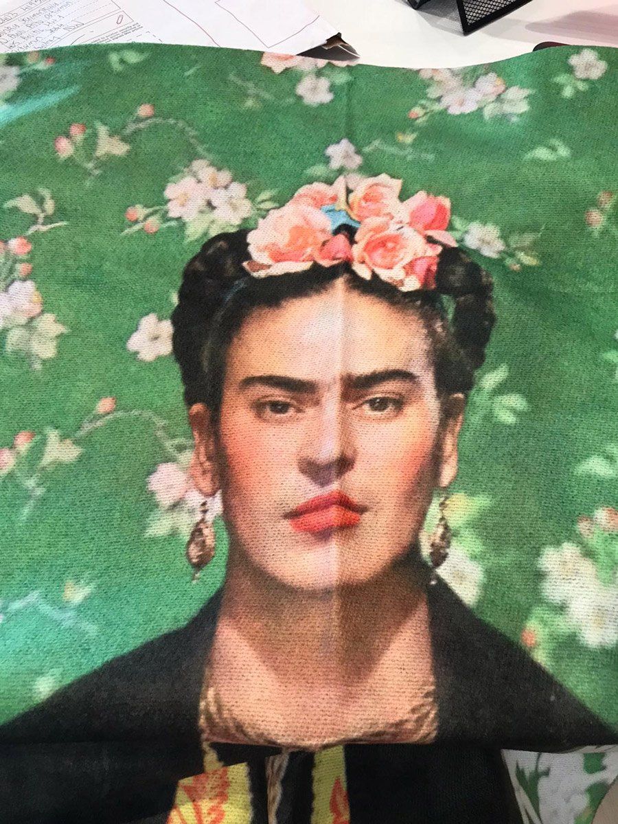 Frida Kahlo portrait with pink floral headpiece against a floral green background.