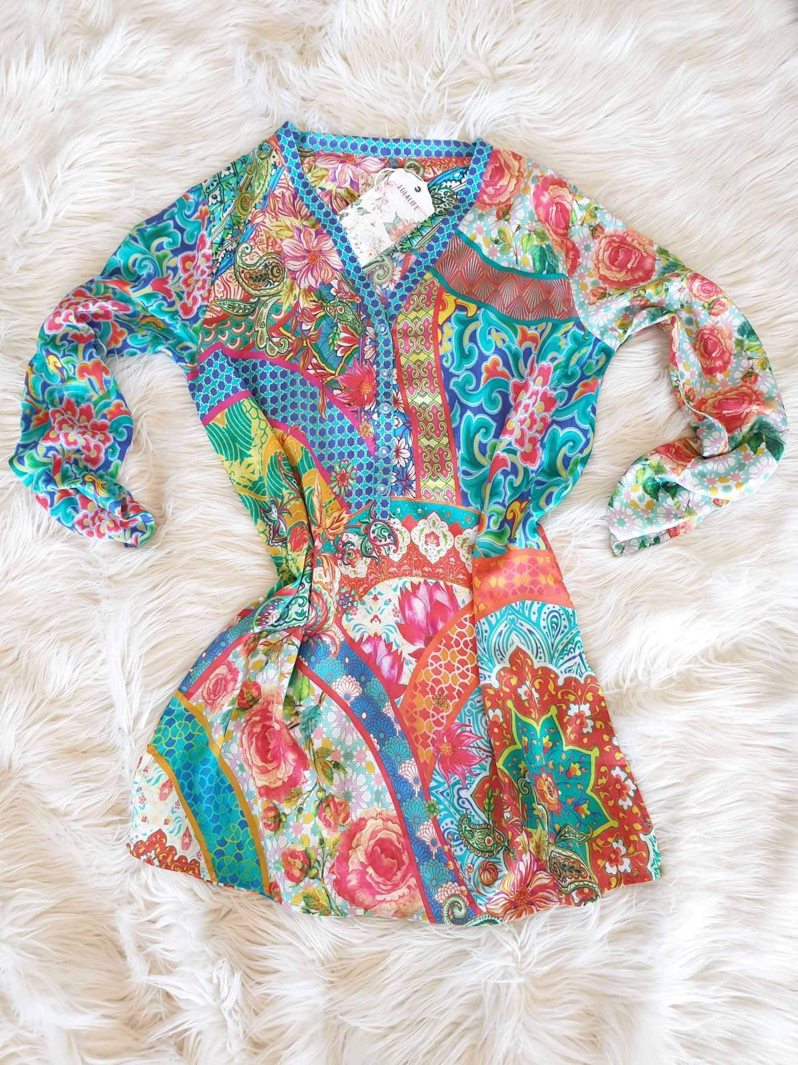 Colorful floral print tunic on fluffy white surface.