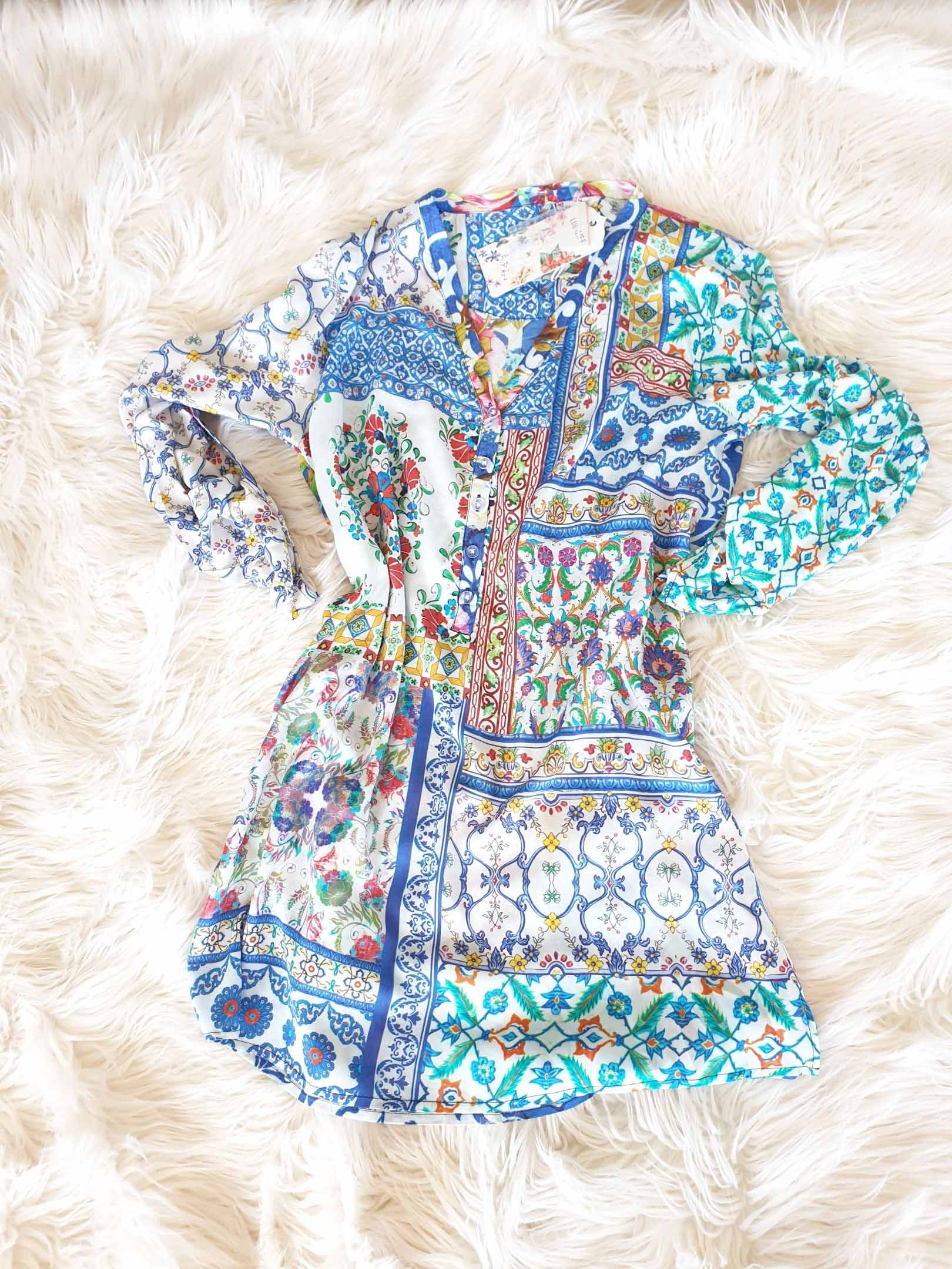 Blue floral patterned dress on a fluffy white surface.