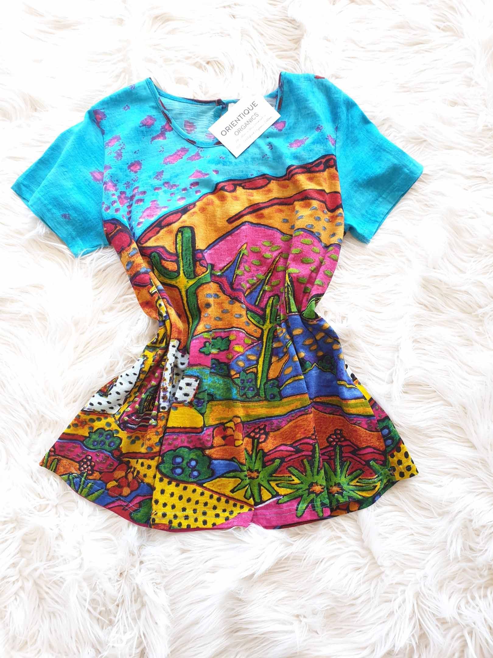 Turquoise short-sleeve shirt with a desert-scene print in vibrant colors.