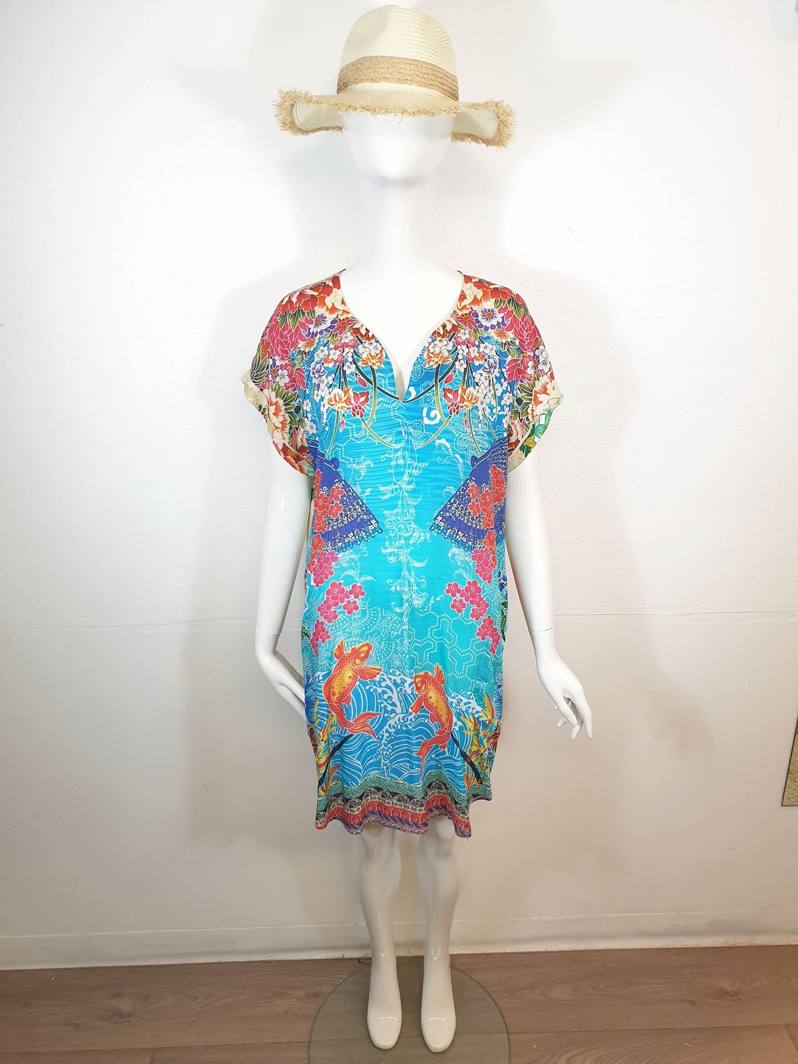 Mannequin in a floral dress with a straw hat, standing in a room.