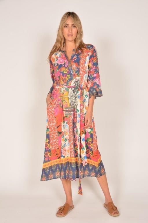 Woman in a colorful patchwork floral midi dress with brown sandals, standing.