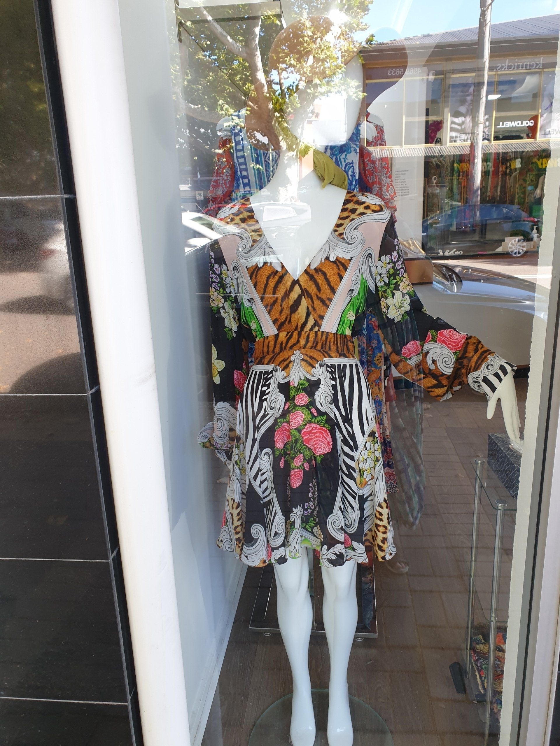 Mannequin in a window wearing a patterned dress with tiger and floral prints.