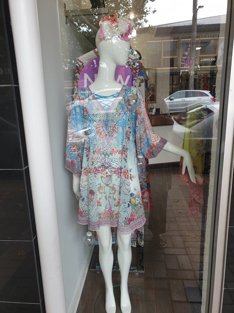 Mannequin in a boutique window wearing a floral print dress and headband.