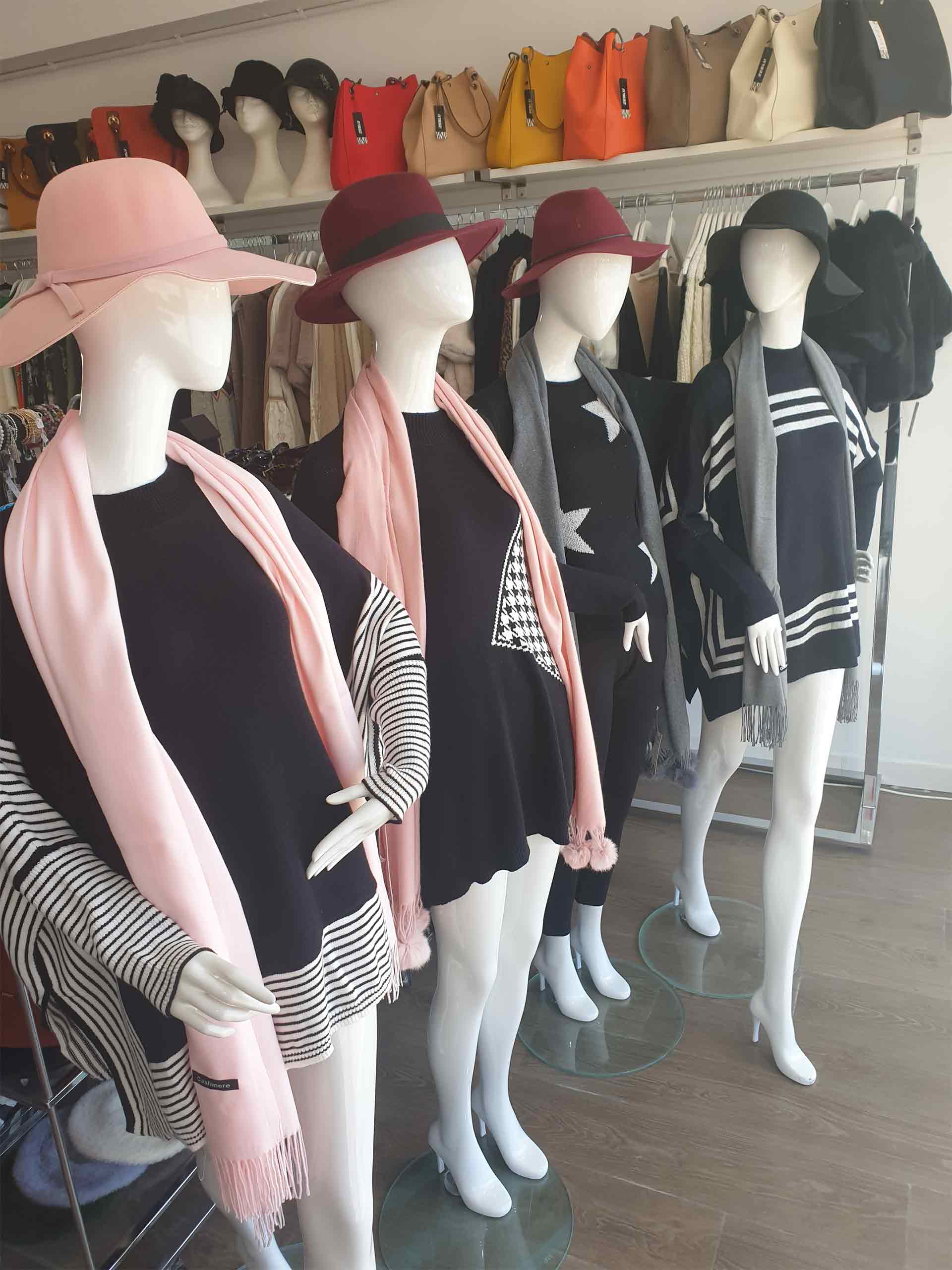 Store mannequins wearing hats, scarves, sweaters and boots, in a retail setting.