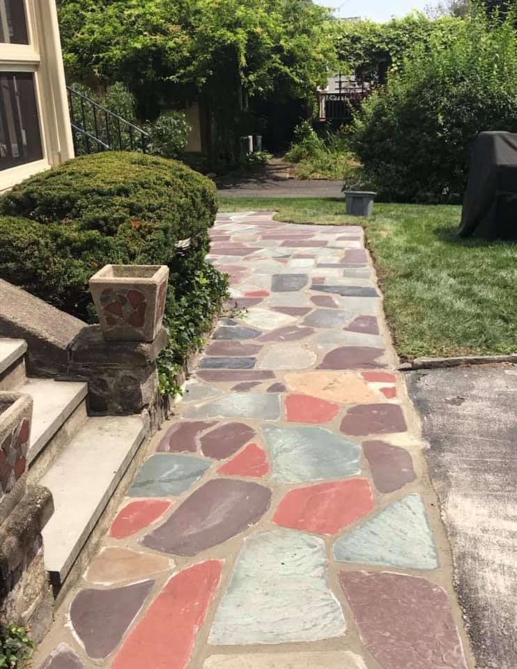 Flagstone walkway leading to a house, with green lawn and foliage.