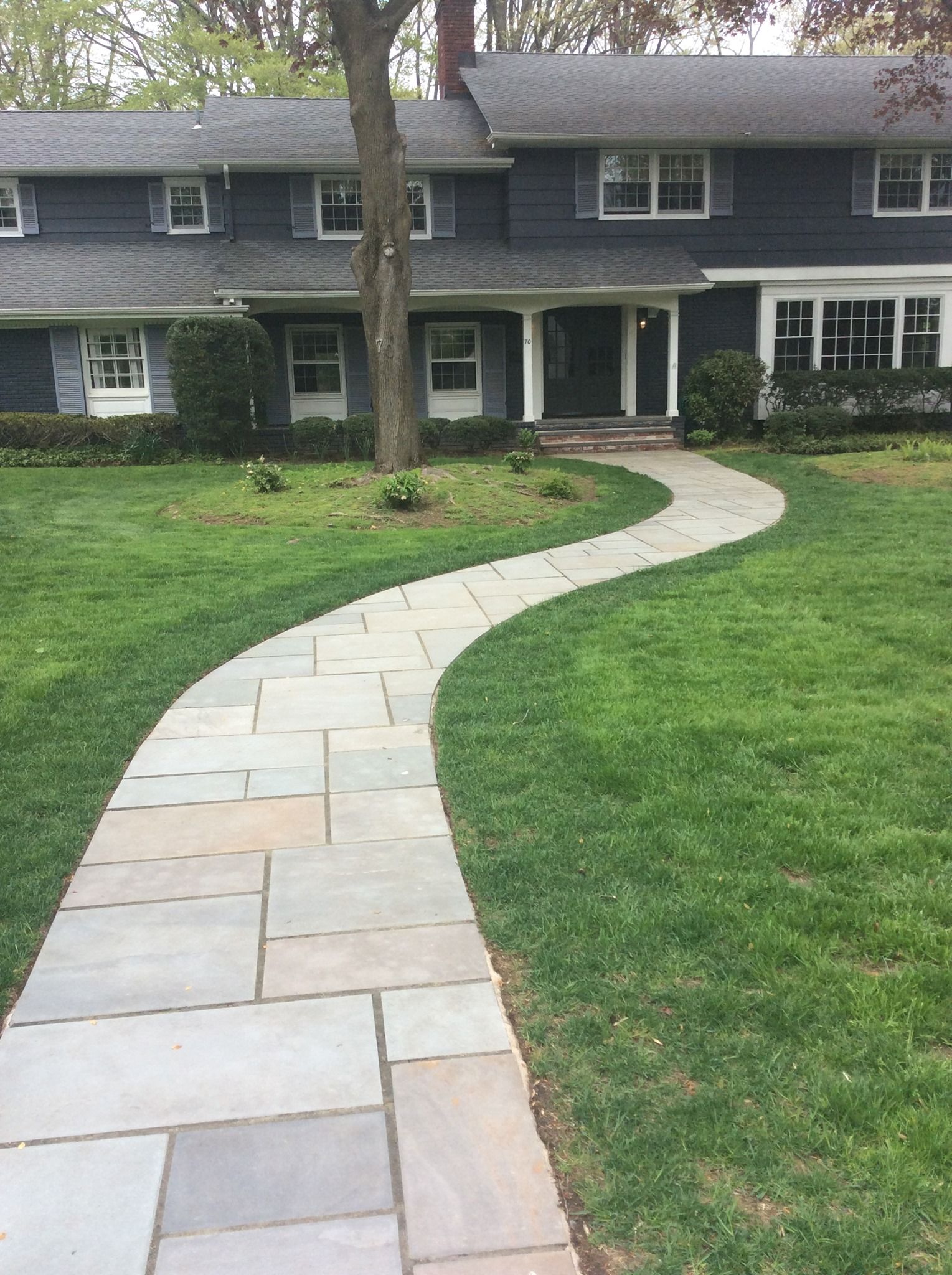 Stone path leads to a blue house with white trim, set in a green lawn.