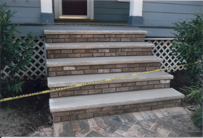 Brick and concrete steps leading up to a house entrance, with caution tape across the steps.