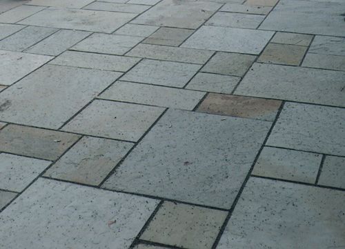 Gray and beige stone patio tiles in a geometric pattern.