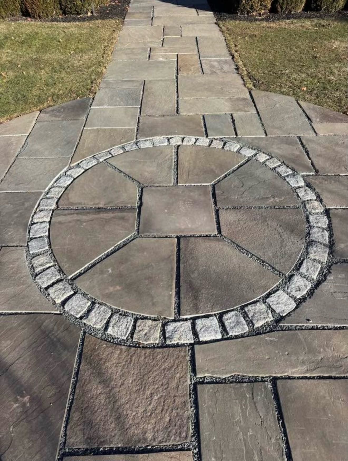 Stone walkway with a wavy design leads to a brick home.