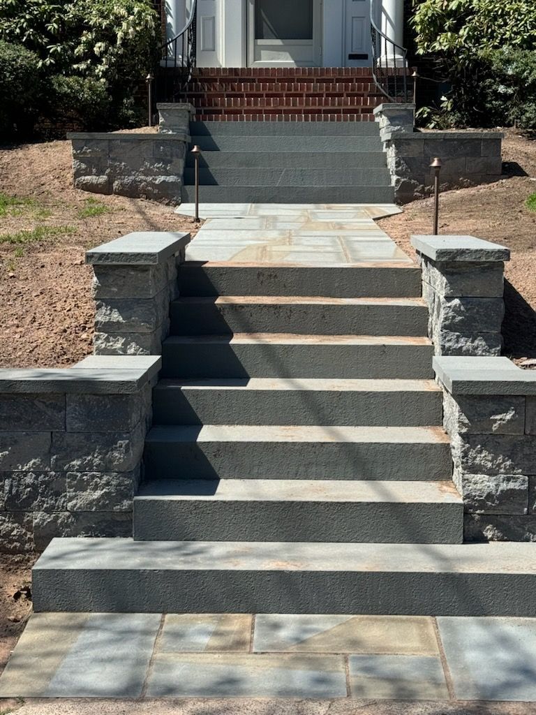 Stone steps leading up to a door with a doormat. Light green siding and a framed crest are visible.