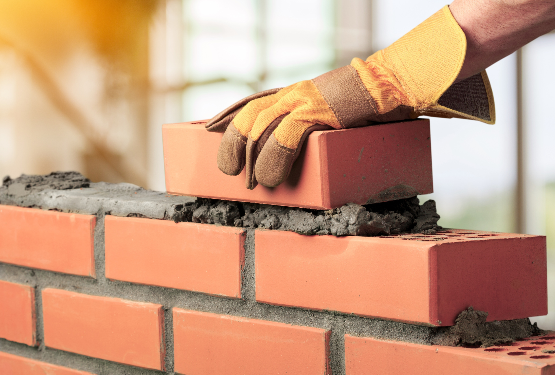 Brick outdoor fireplace with a fire burning, on a brick patio in a backyard with grass.