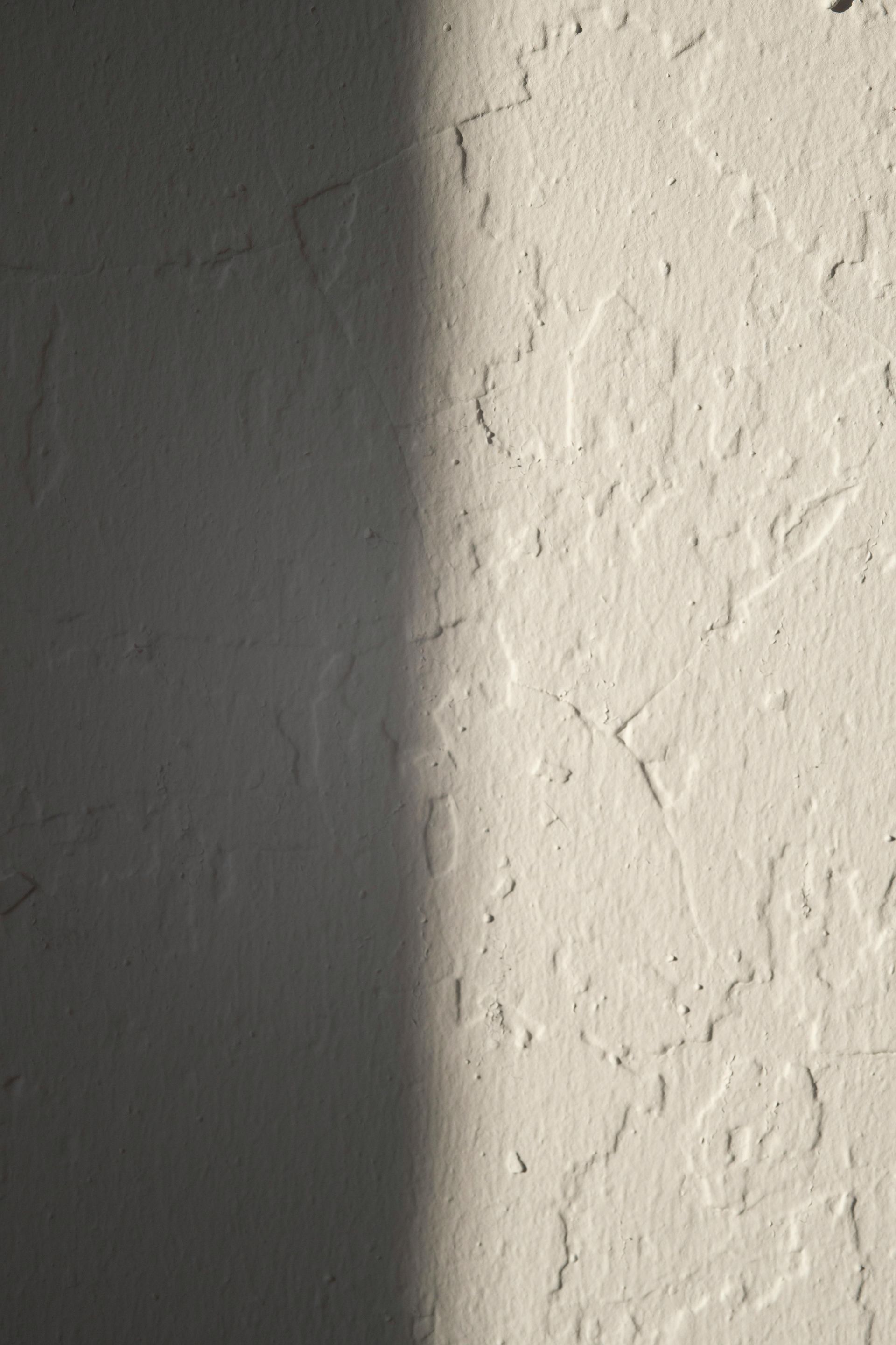 Textured off-white wall with a dark vertical shadow down the left side.
