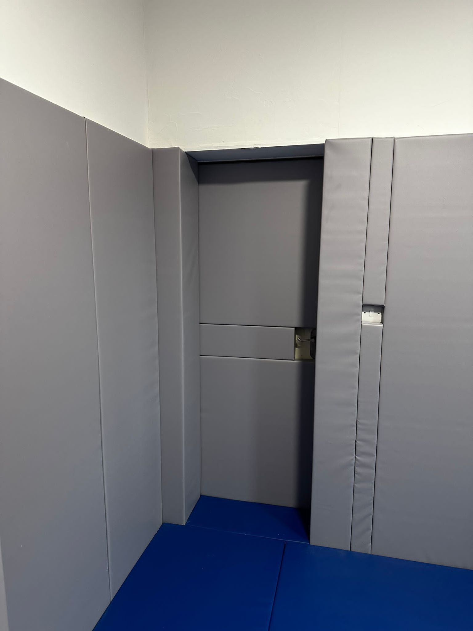 room with gray padded door and walls and a blue padded floor