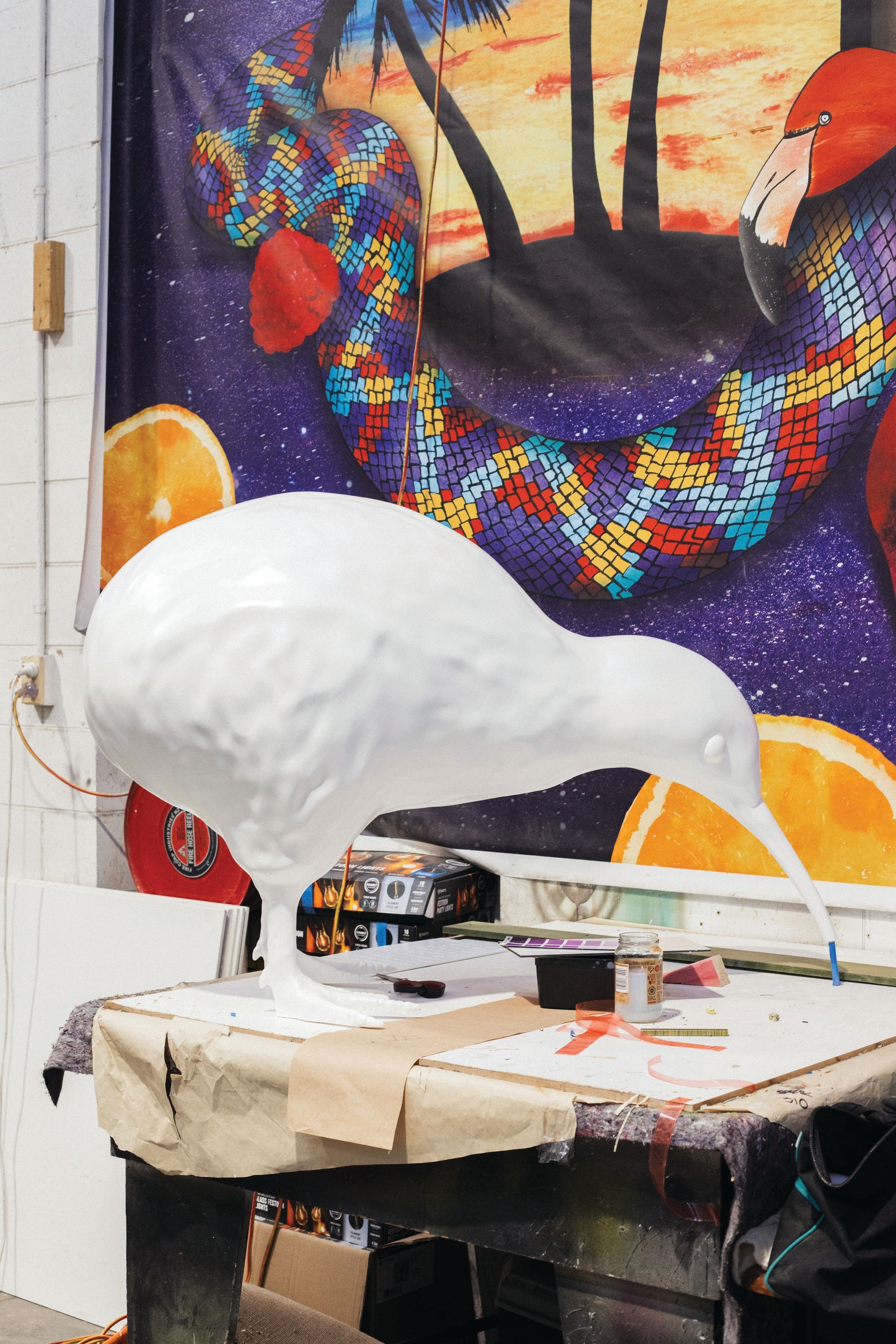 A white bird is sitting on a table in front of a painting