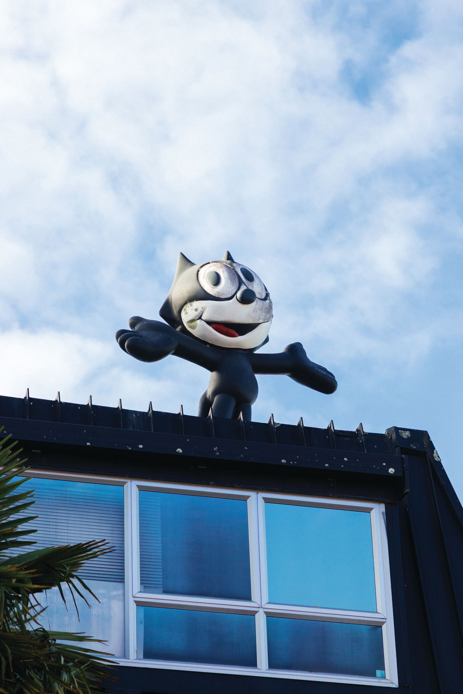 A felix the cat statue is on the roof of a building