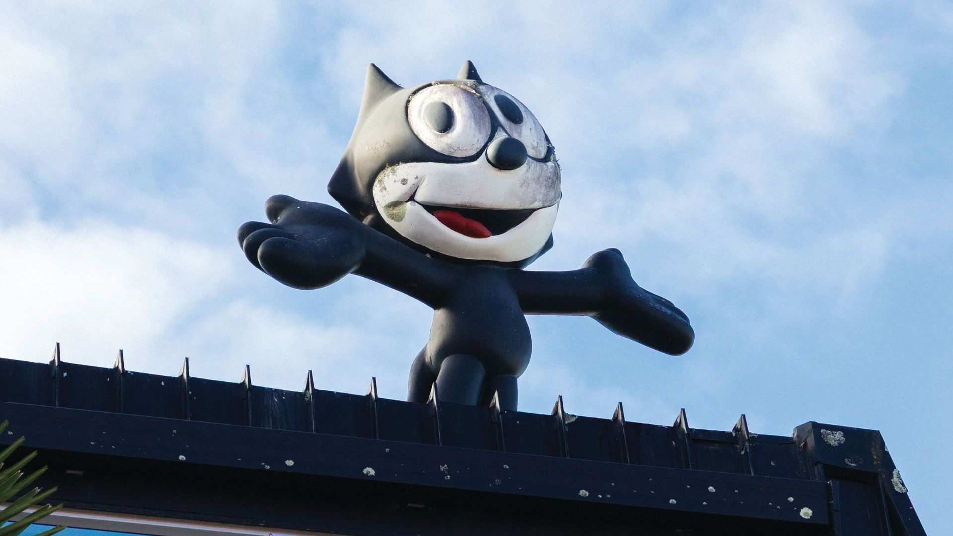 A felix the cat statue is on the roof of a building