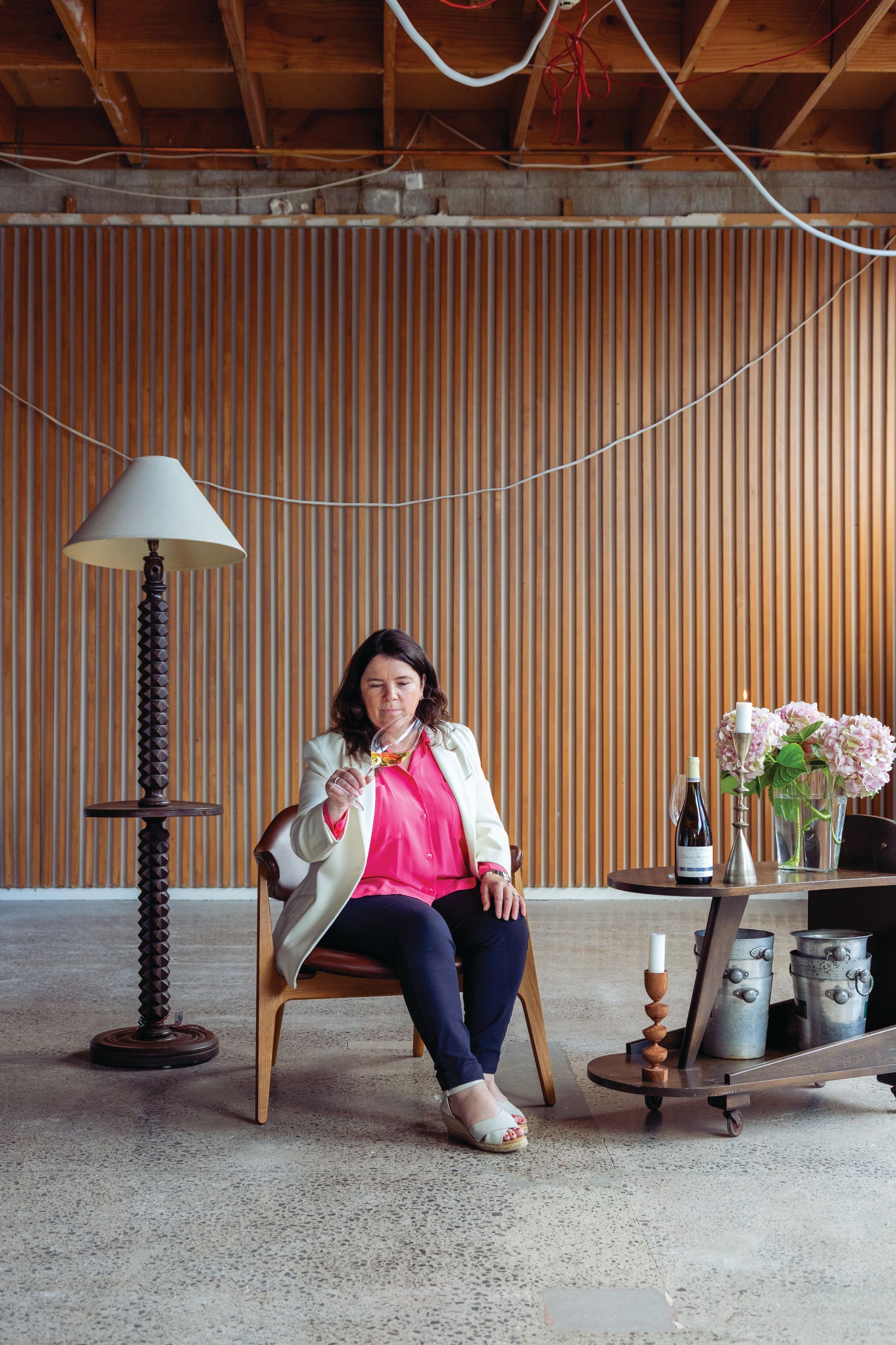 A woman is sitting in a chair drinking a glass of wine.